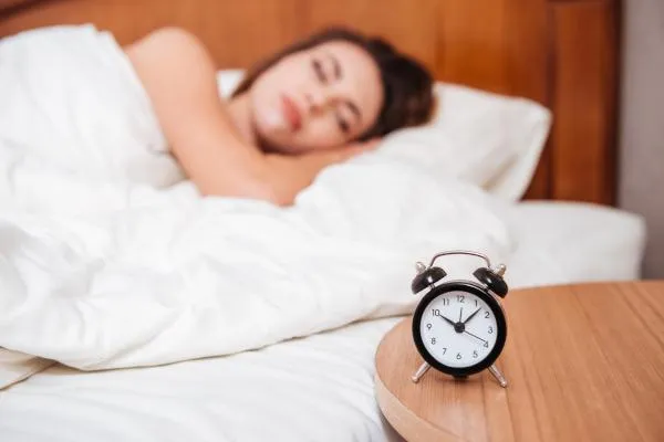 girl sleeping with an alarm next to her