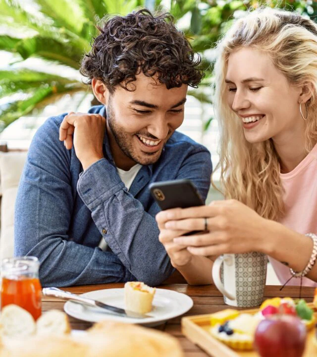 couple enjoying their breakfast while using their phone